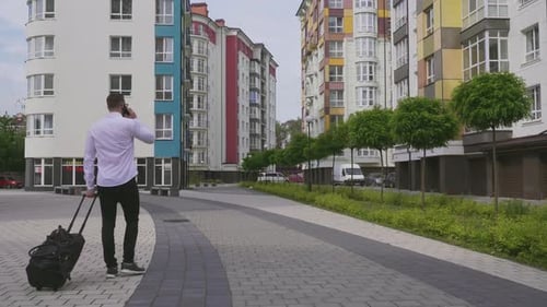 Man With Suitcase Walks and Talks on Phone