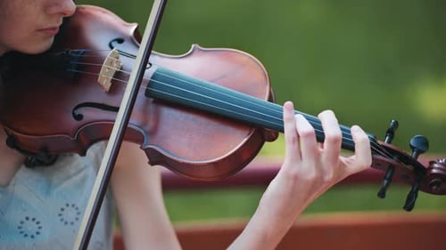 A Young Girl Plays the Violin in the City Park
