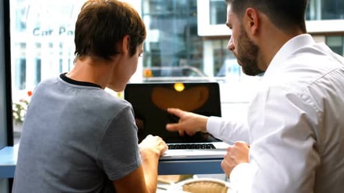 Two People Collaborating on Laptop in Urban Setting