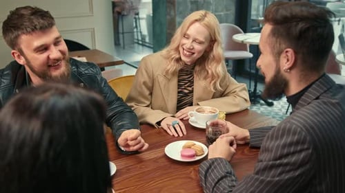 Beautiful girl is having fun in the company of happy friends in a coffee shop. Friends drink coffee.