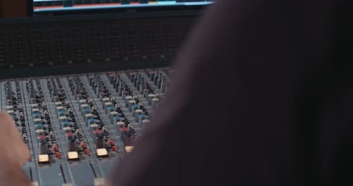 Sound engineer working in a recording studio with a sound console and microphones