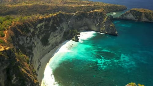 Ocean Waves, Cliffs and a Tropical White Sand Beach in Nusa Penida Island, Bali in Indonesia. Aerial