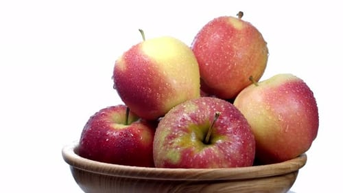 Red and Yellow Apples on a White Plate on a Wooden Plate Rotate.
