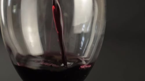 Pouring red wine into a glass close up