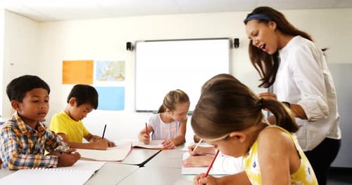 Teacher assisting school kids with their classwork in classroom