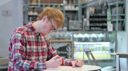Man Works Indoors in an Urban Cafe Setting