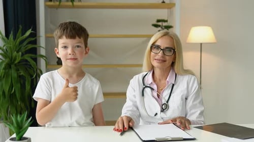 Smiling Senior Female Family Doctor in Uniform Consulting Little Kid Patient at Checkup Meeting in