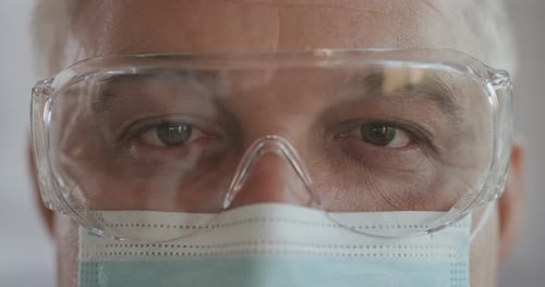 Portrait of Confident Doctor Man Face, Close-up. Eyes with Safety Glasses and Protective Mask