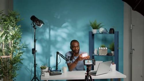 Mann zeigt Produkt vor der Kamera und filmt Vlog