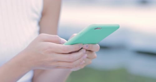 Woman's Hands Using a Turquoise Mobile Phone