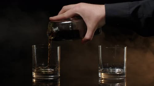 Whiskey Pouring from Bottle into Two Glasses
