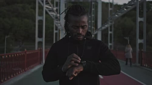Active African American Man Using Activity Tracker on Smartwatch Before Run Workout Standing on City
