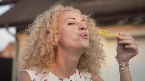 Woman Blowing Bubbles Outside on a Sunny Day