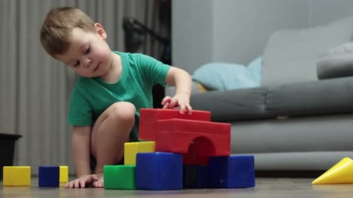 Little Kid Boy Building Tower Garage From Colorful Plastic Cubes Blocks on Floor