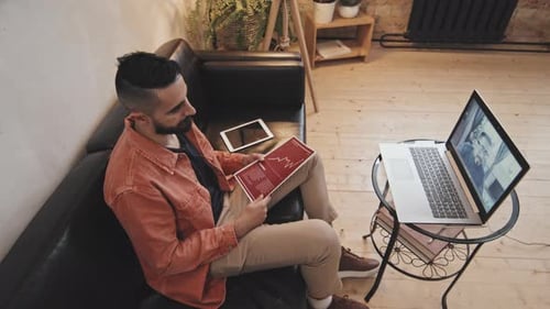 Man Works at Home with Laptop and Tablet