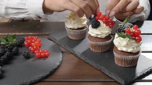 Woman Decorating Cupcakes with Fresh Berries
