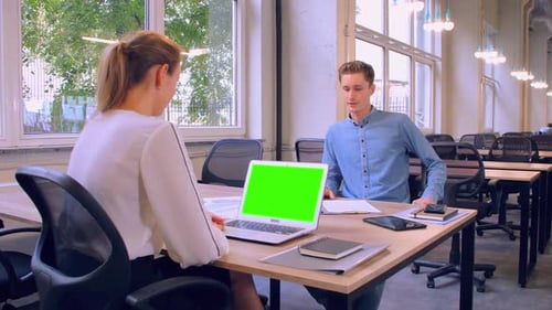 Two Cheerful Colleagues Discussing in Modern Office