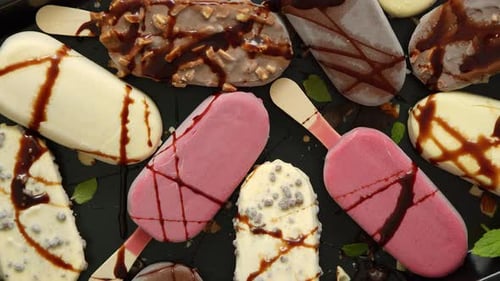 Eiscreme auf Stick, beschichtet mit verschiedenen Schokoladenglasuren und Toppings. Ansicht von oben, flach aufliegend
