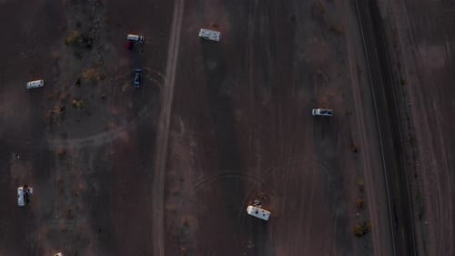 Aerial top-down view of motorhomes parked in the desert at golden hour