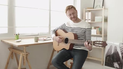 Man Plays Acoustic Guitar in Bright Room