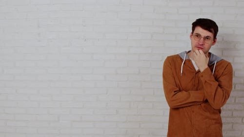 Young Adult Standing, Thinking Against White Brick Wall