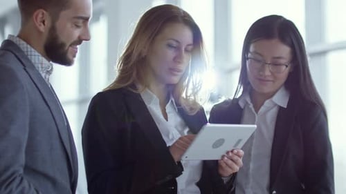 Business Team Collaborates on Tablet in Modern Office