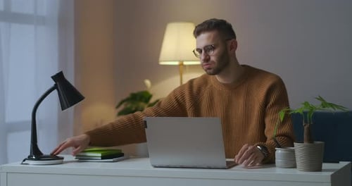 Man Working on Laptop, Rubs Eyes in Tiredness