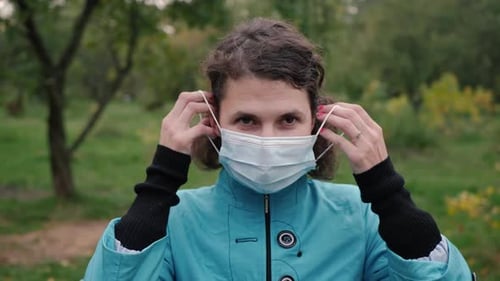 Woman Puts On Surgical Mask Outdoors
