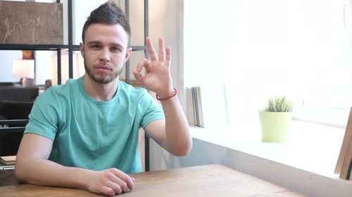 Man Makes Ok Sign at Wooden Table