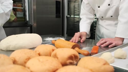 Chefs are preparing pastry dough, baking bakery food on a stainless steel table.