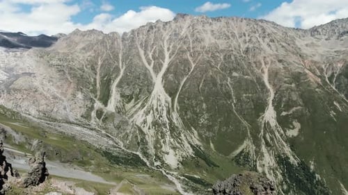 Rocky mountains with clouds among the tops of the rocky hills and blue sky