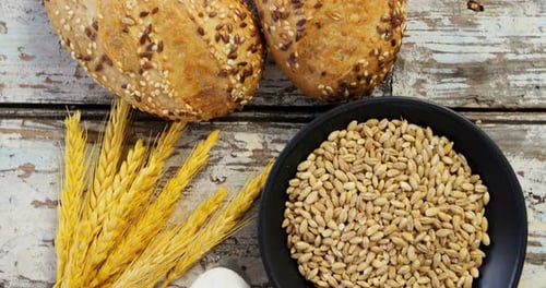 Wheat grains with bread buns, oats and spoon full of flour