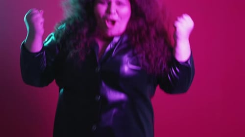 Woman with Curly Hair Jumps in Front of Pink