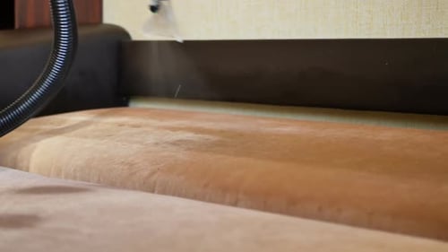 Vacuum Cleaner Sprays Cleaning Solution Onto the Sofa Cleaning Furniture