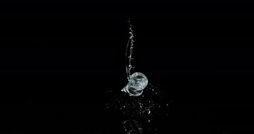 Glas Wasser prallt und spritzt auf schwarzem Hintergrund, Zeitlupe 4K