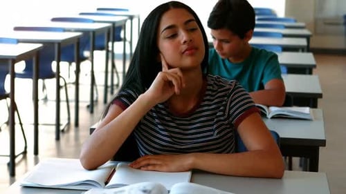 Sleepy girl relaxing on desk while studying in classroom