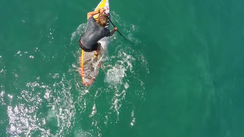 Aerial view of a man sup stand-up paddleboard surfing in Hawaii
