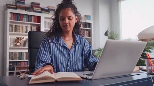 Woman Working on Laptop and Using Book