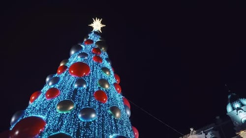 Festively decorated green Christmas tree with toys, colorful balloons,