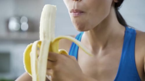 Woman Eats Healthy Banana in Kitchen