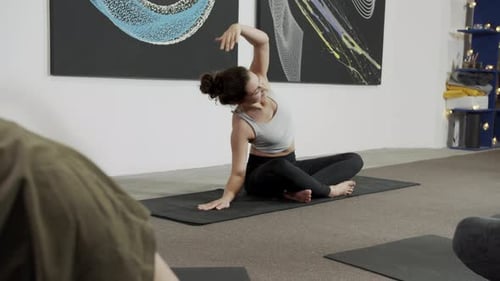 Young Woman Practicing Yoga with a Team White Wall in Yoga Studio