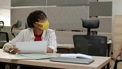 Two Adults Reviewing Documents in Office Wearing Masks