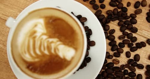 Nahaufnahme einer Kaffeetasse mit Untertasse und Kaffeebohnen