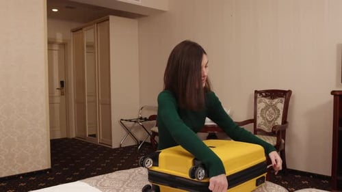 Woman Packing Yellow Suitcase in Hotel Room