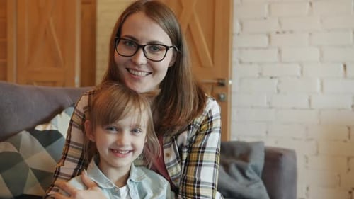 Smiling Woman and Girl Sitting on Couch Indoors