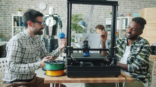 Young People Talking Watching 3d Printer Modeling Plastic Detail for Cool Robot