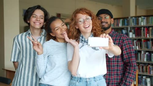 Portrait of Happy Students Taking Selfie in Library with Smartphone Camera