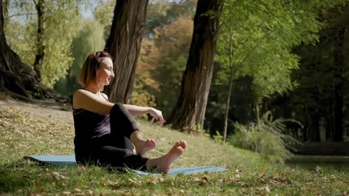 Weitblick einer Frau, die auf einer Yogamatte sitzt und an sonnigen Tagen im Freien Yoga macht