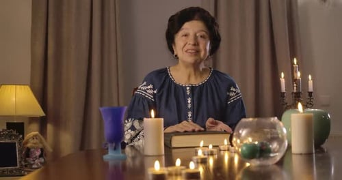 Woman Reads at Table Lit by Candles