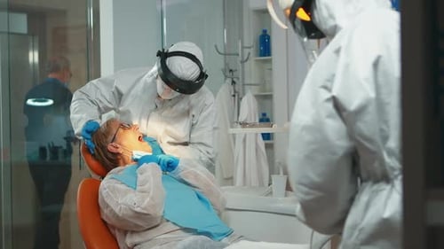 Dentist Examining Patient in Full Protective Gear